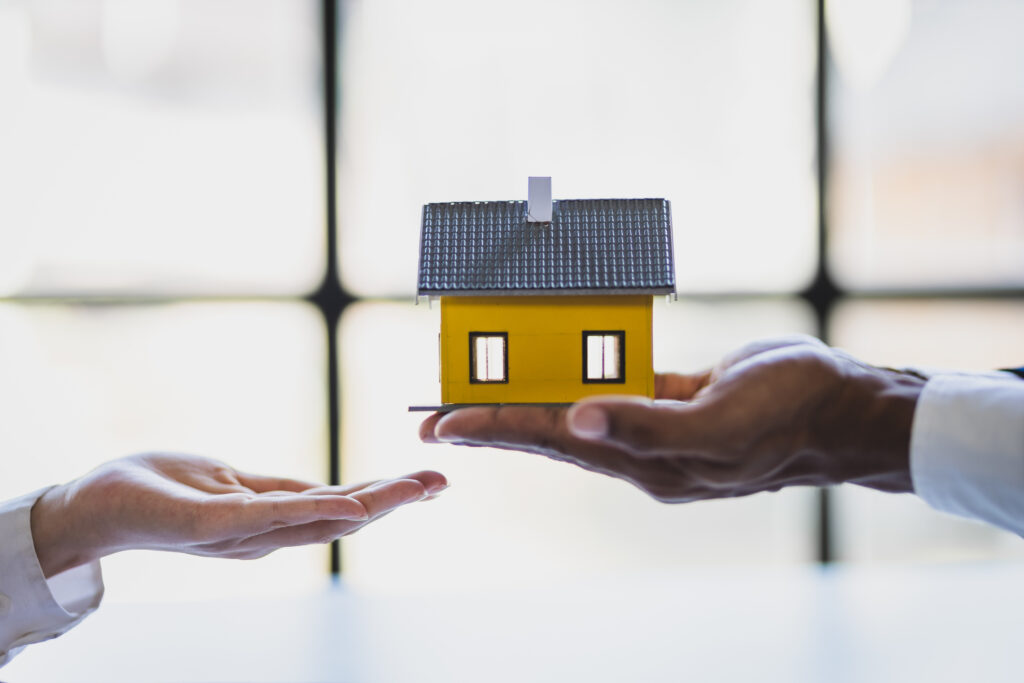 Person with small house in hand representing estate planning and property tax transfers
